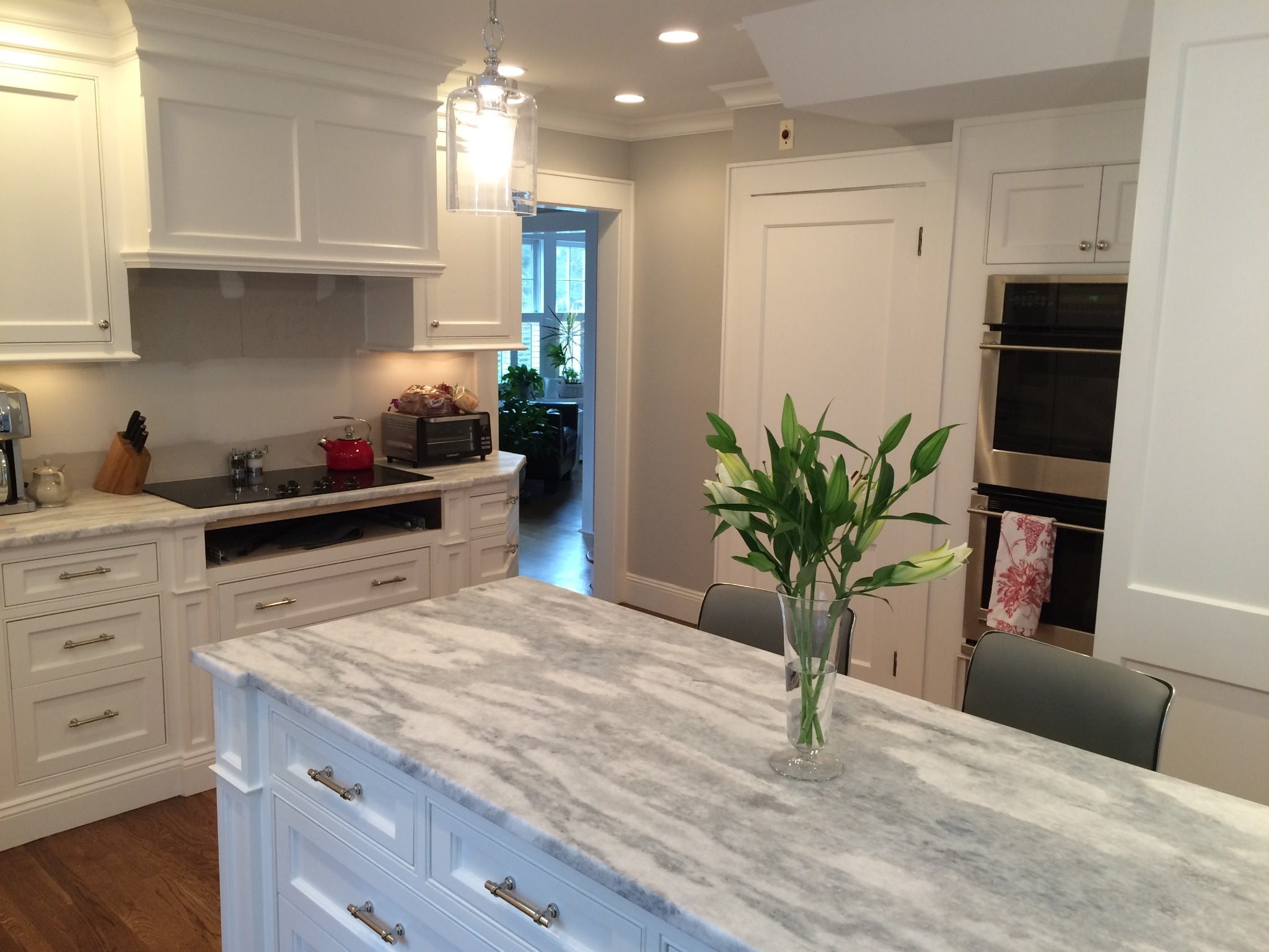 Bright finished white custom kitchen with marble island and fitted cabinetry